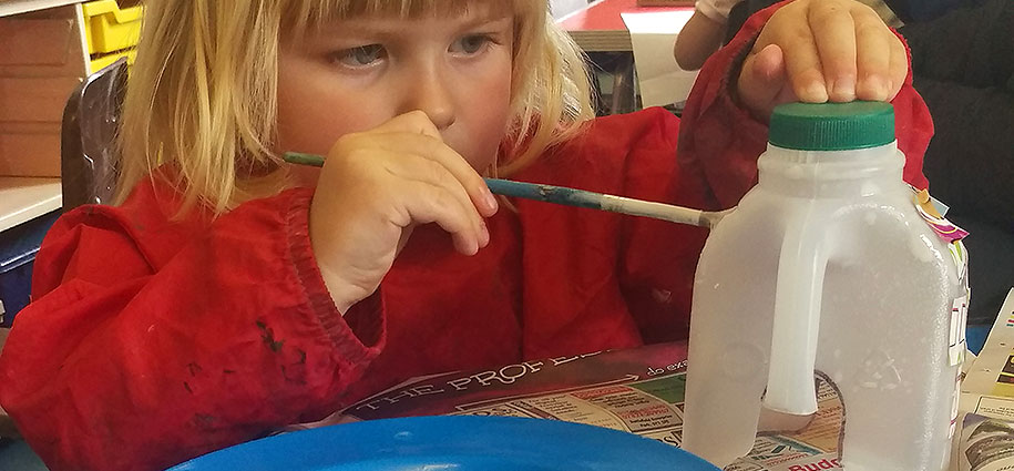 young girl painting a bottle